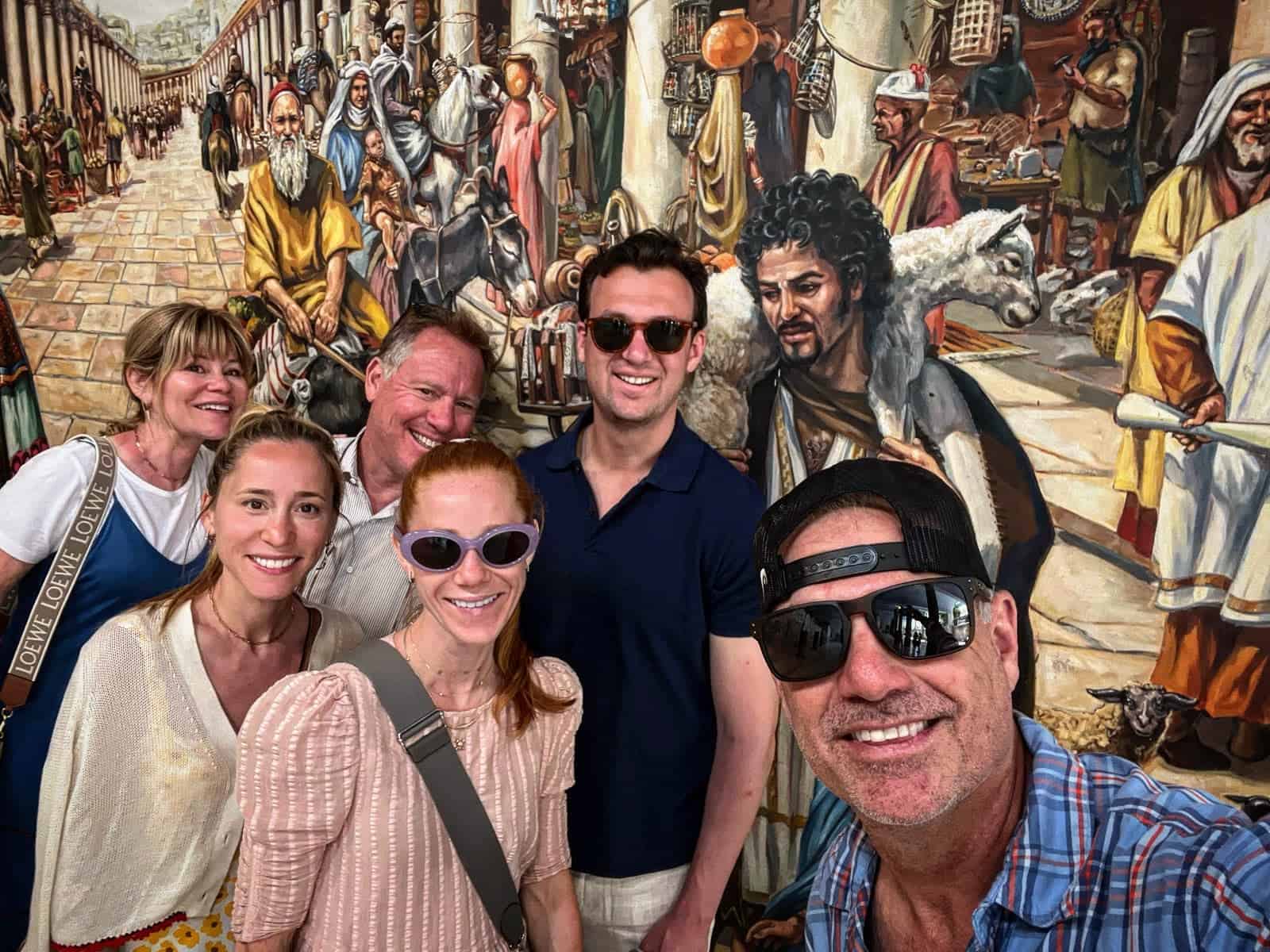 A group of people posing for a photo in front of a mural.