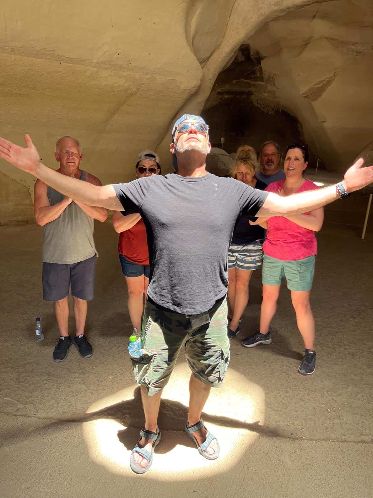 A group of people standing in a cave with their arms outstretched.