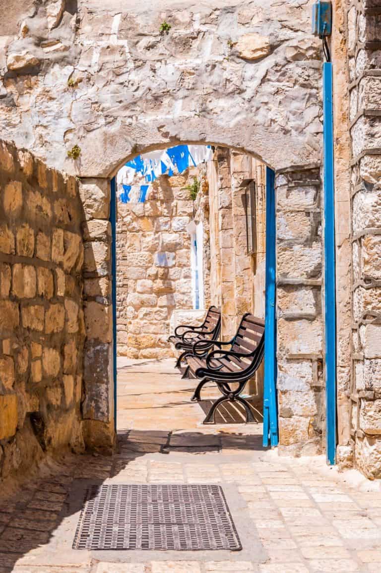 A stone archway with benches in front of it in Tzefat, Israel.