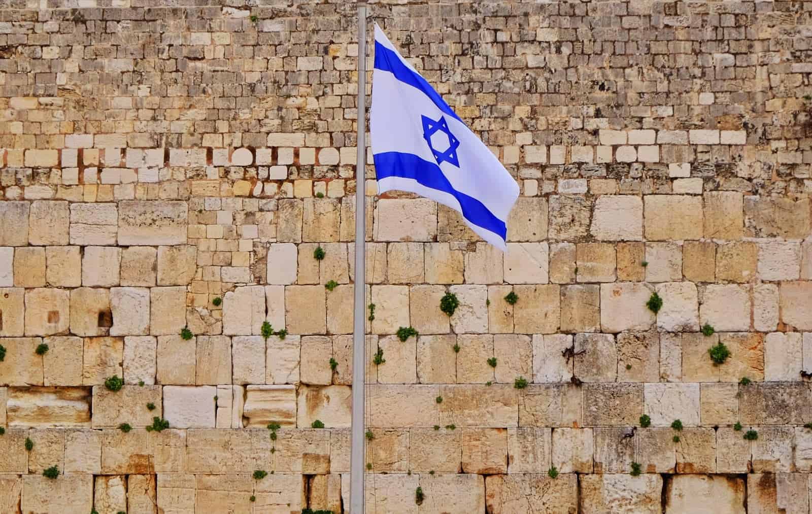 An israeli flag flies in front of a the western wall.