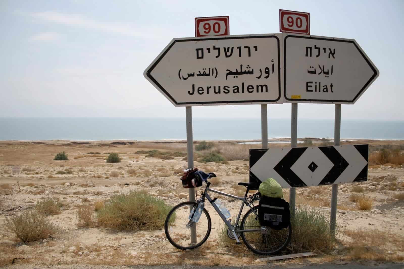 A tourist bicycle is leaning against a sign that says Jerusalem and Egypt.