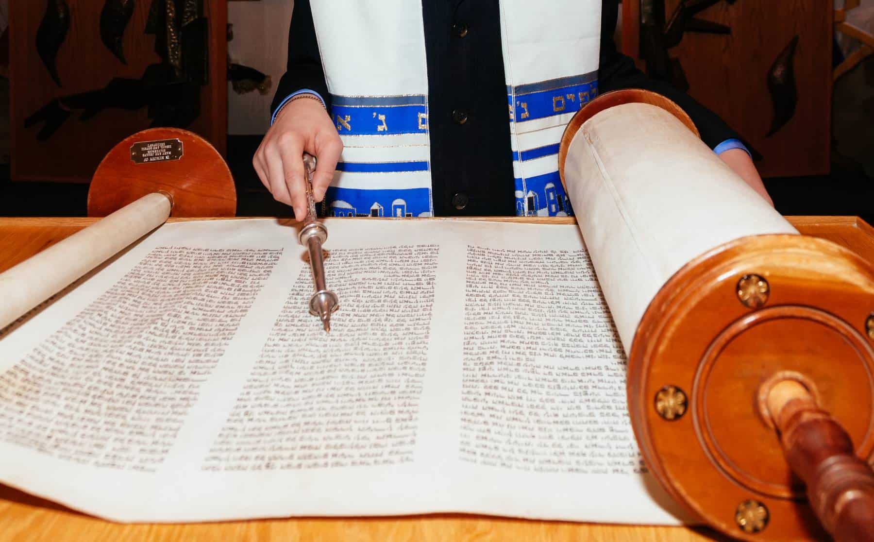 A person reading from a torah scroll with a yad (pointer).